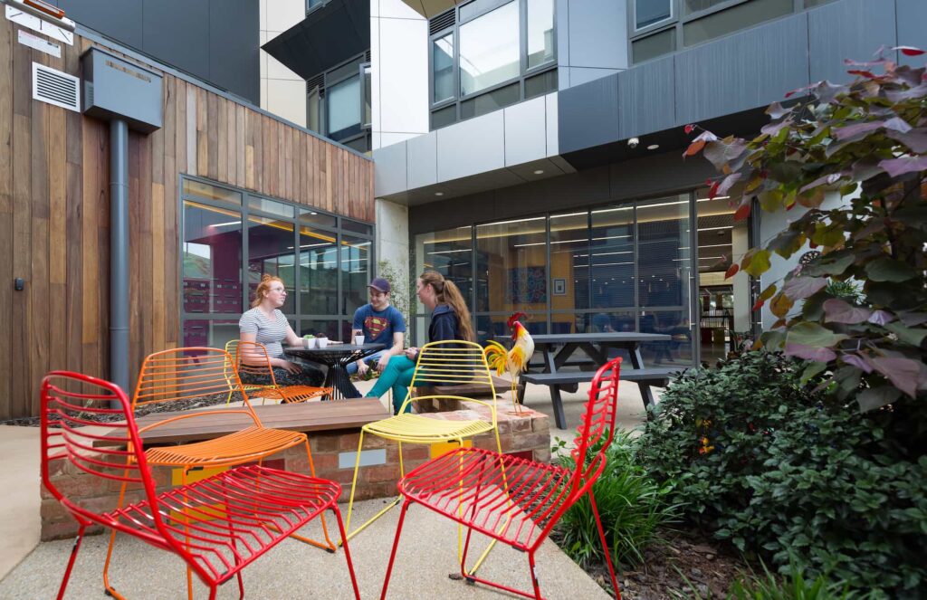 three people sitting in a courtyard of an education building