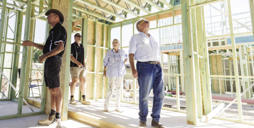 Builder and owners inspecting house frame